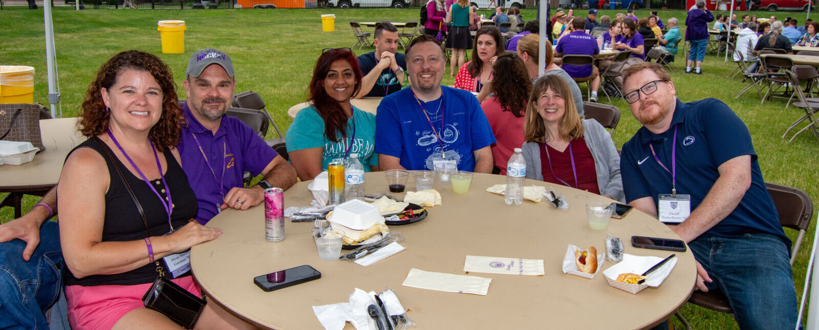 A group of alumni smile while sitting around a table outside during Reunion