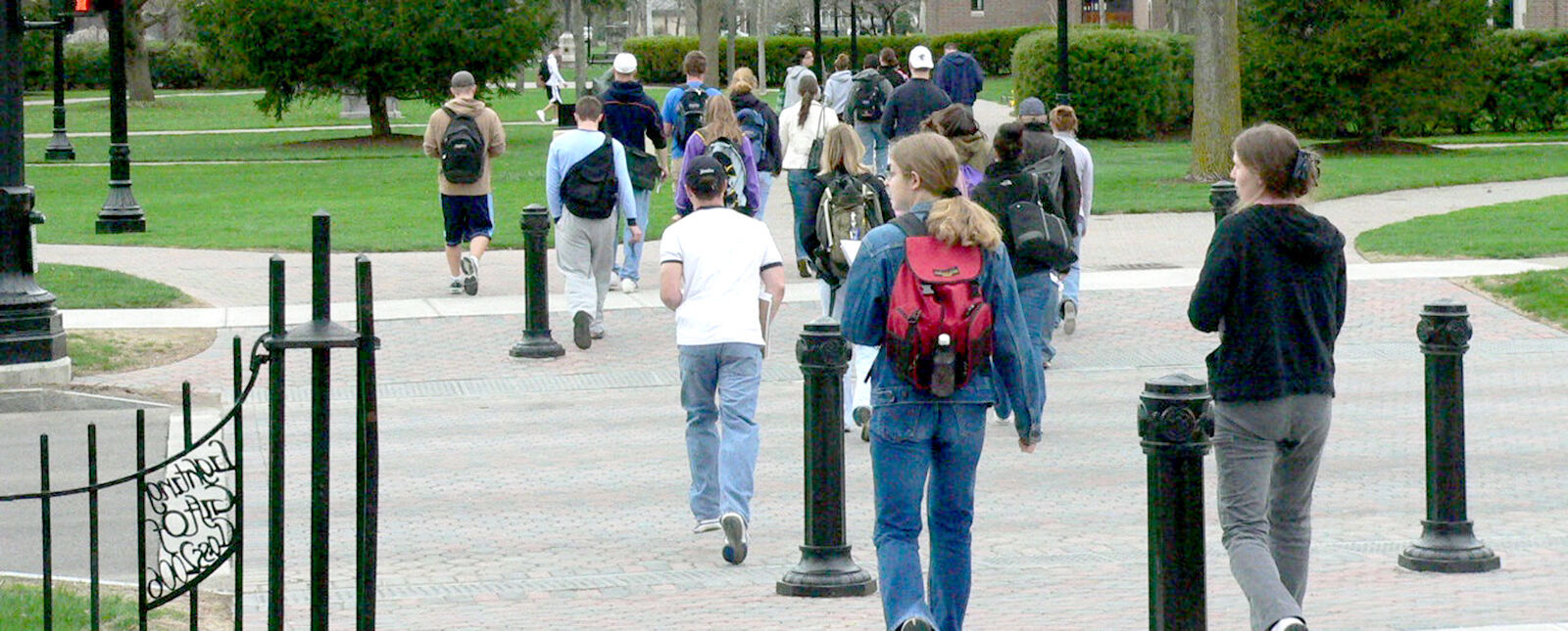 A large group of students leaving class walk across Park Place 