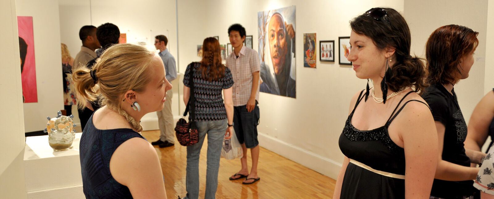 Two female students chat during an art show in the George Waters Gallery