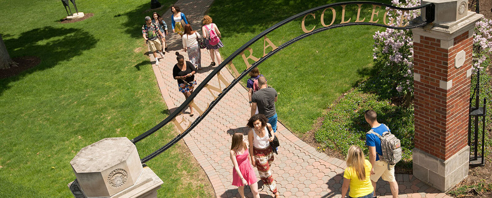 Students make their way to class while passing under an archway that says Elmira College