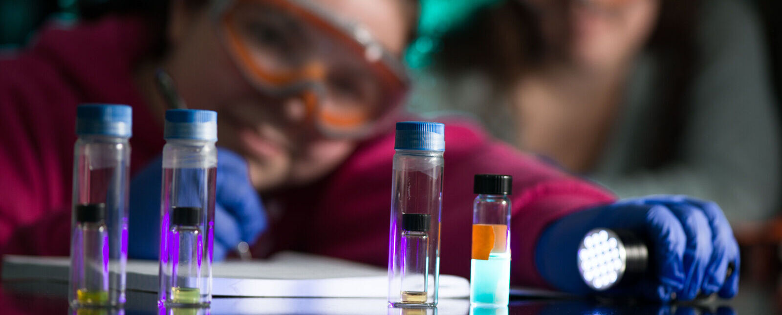 一个化学学生在化学实验室里用灯照着装着不同物质的小瓶