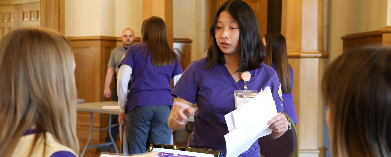 A nursing student gives directions to other students during a public health simulation.