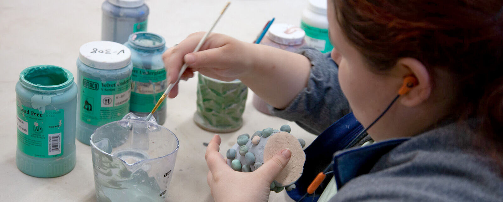 A female student paints a ceramic piece