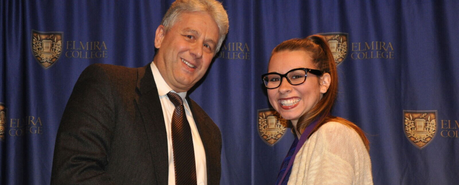 President Lindsey shakes hands with a female student during a recognition ceremony