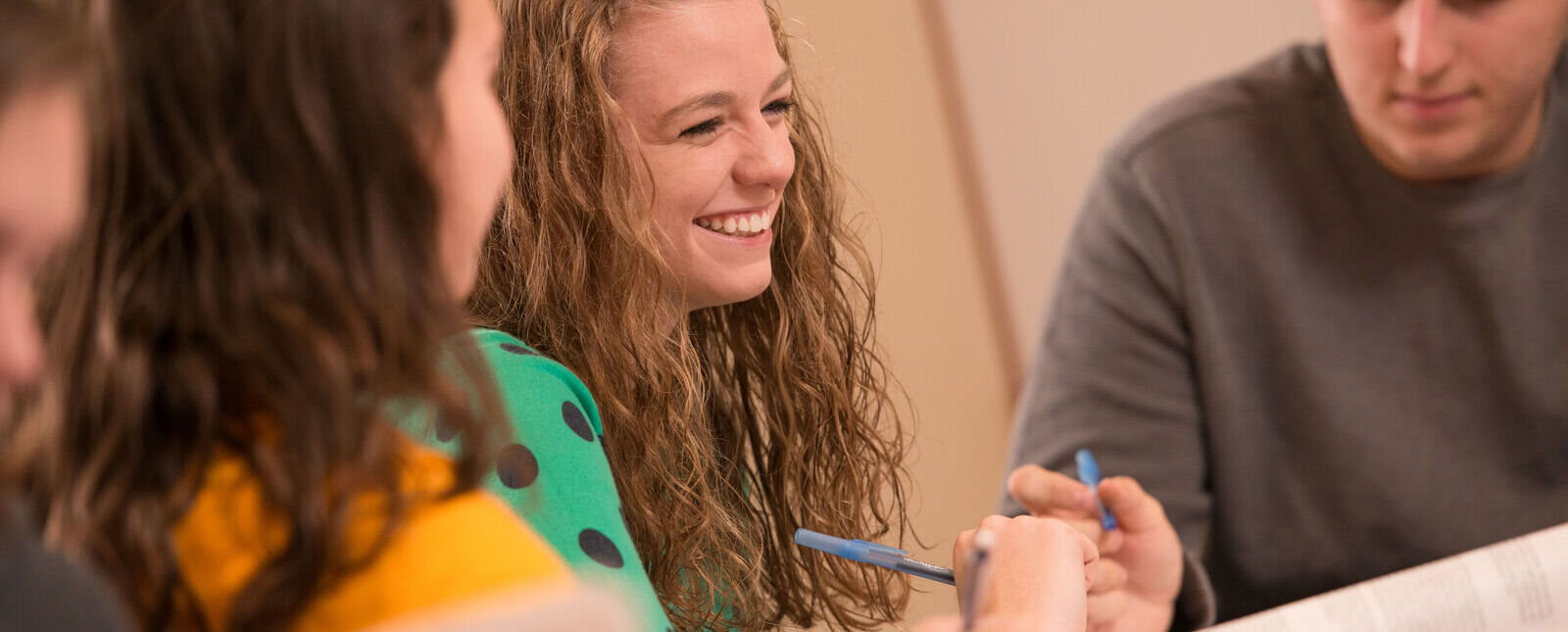 A female student smiles while working on a class assignment with a group