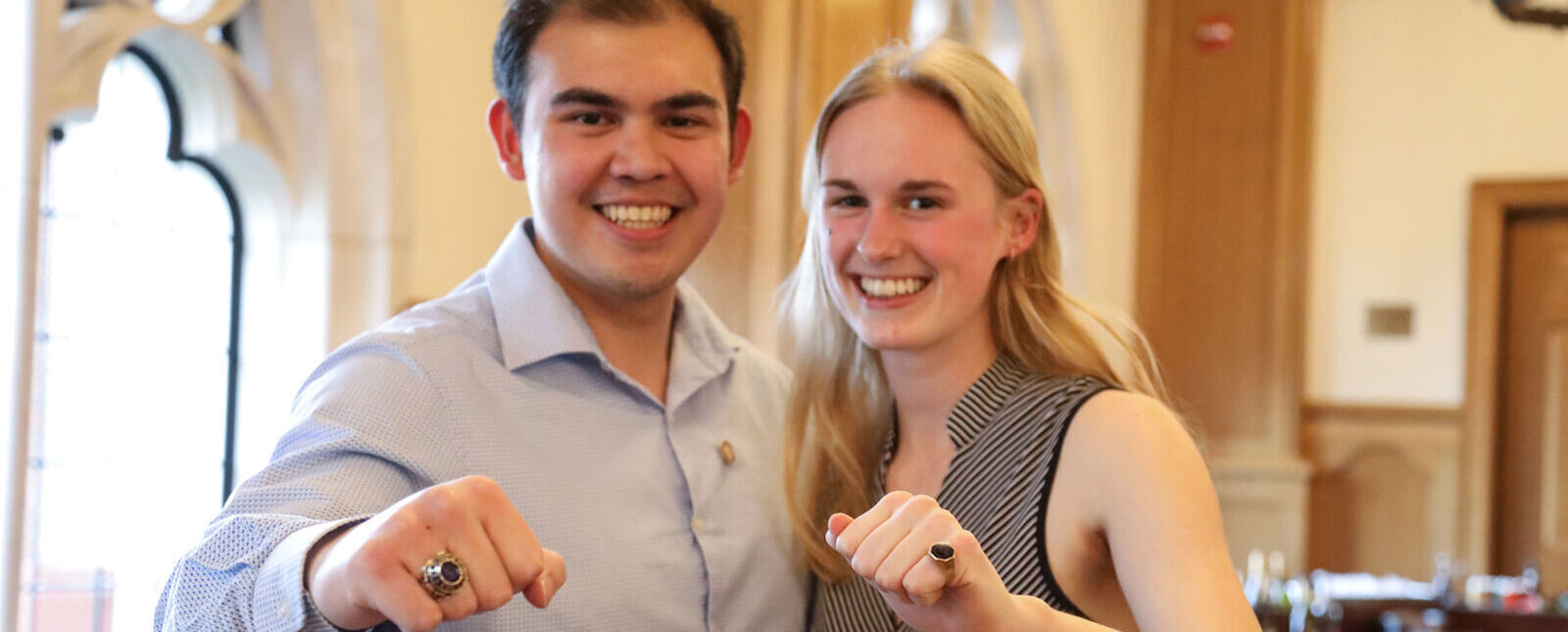 A male and female student show off their class rings