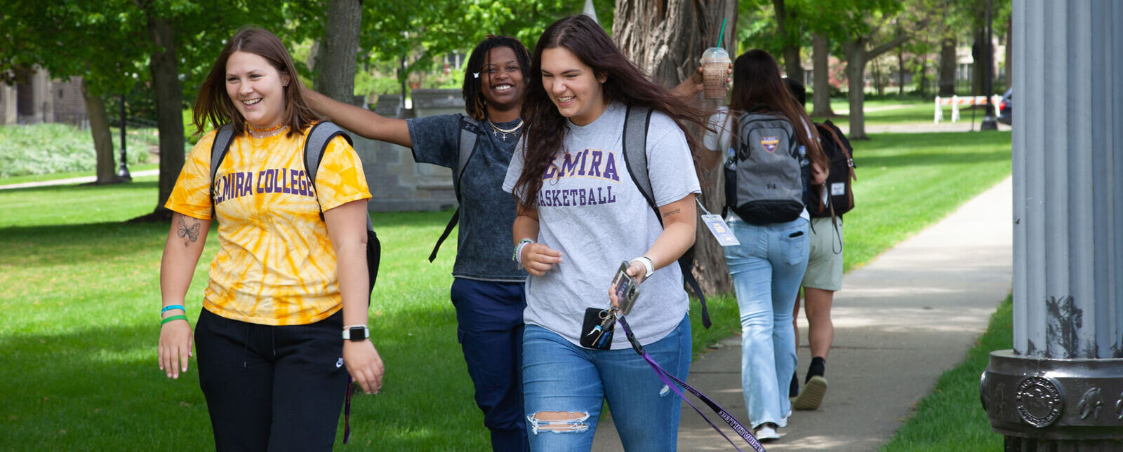 A group of students smiles as they walk across campus.