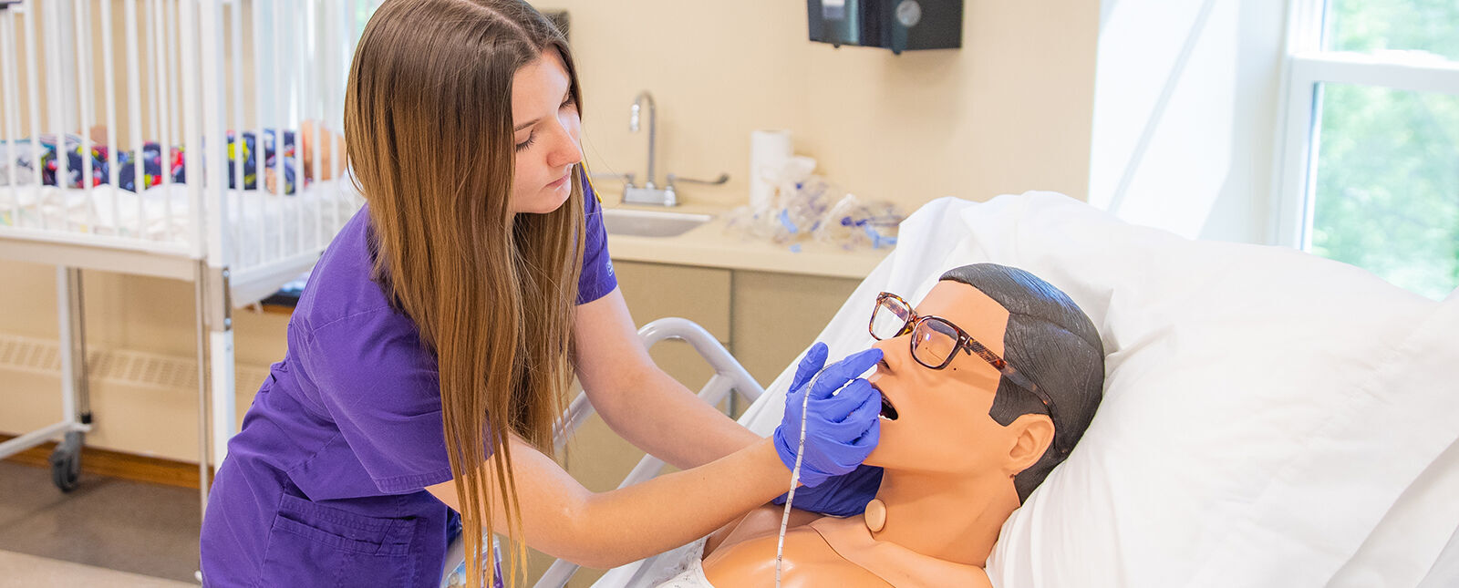 A female Nursing student practices an examination on a dummy