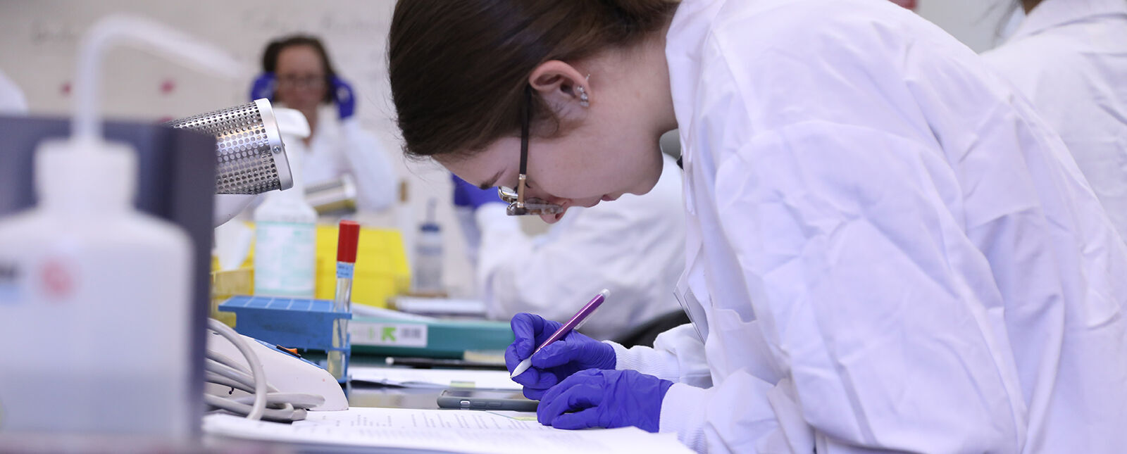 A female student writes notes in a lab