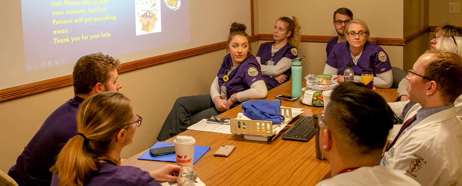 Nursing students listen to LECOM faculty present information in a meeting room
