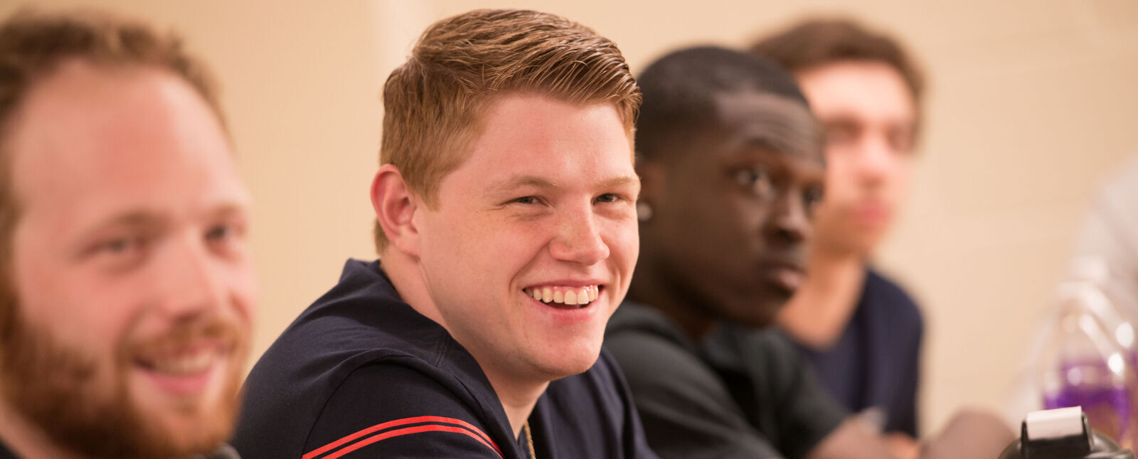 A male student smiles while listening in a class