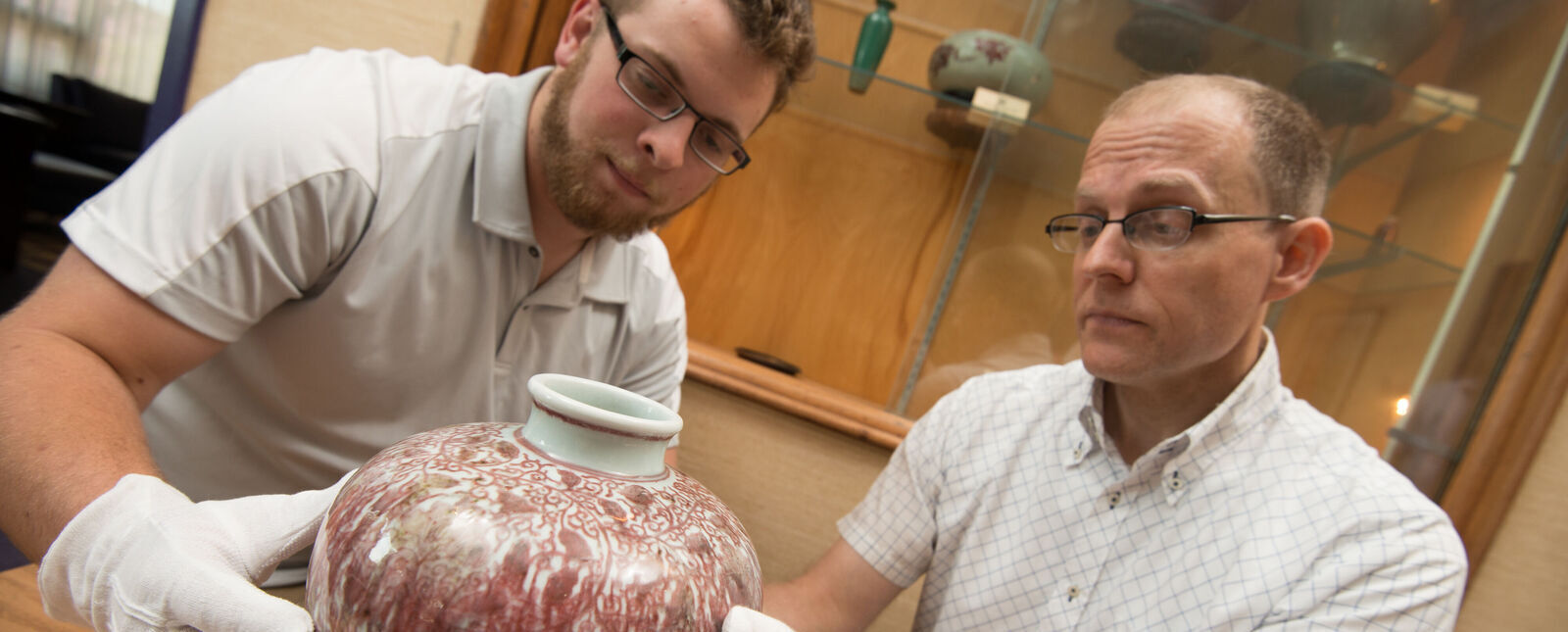 A student and professor examine pottery